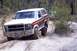 1982 Ford Bronco - A white and maroon Ford Bronco navigates a sandy, wooded trail with another vehicle visible in the background.