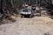 1982 Ford Bronco - A convoy of off-road vehicles navigates a challenging dirt trail through a wooded area.