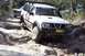 1982 Ford Bronco - Nissan Patrol tackling a challenging rocky path, with a second vehicle following.