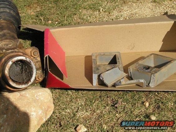 Driveshaft U-joint and broken metal parts in a cardboard box