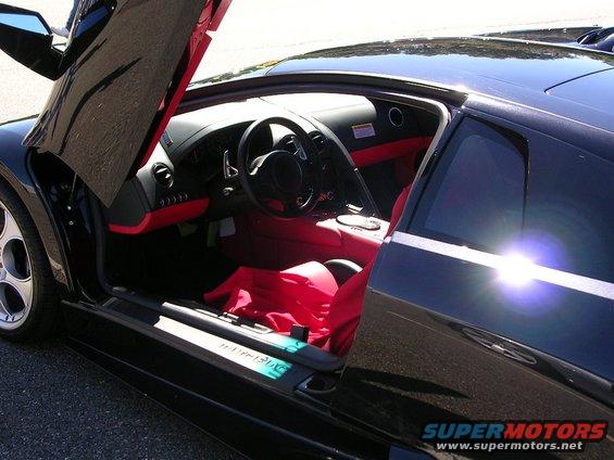Black sports car interior with red seats and butterfly doors open