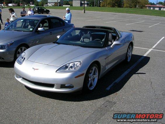 Silver convertible sports car, front 3/4 view, parked in a lot