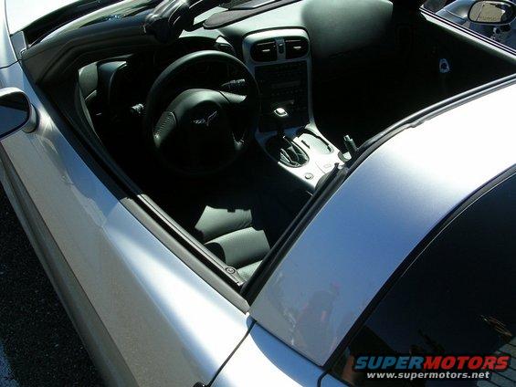 Interior of a silver convertible with black leather seats, steering wheel, and center console. A 'Supermotors' watermark is visible