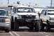 1990 Ford Bronco - A modified 1990 Ford Bronco is parked in a lot, flanked by other vehicles.