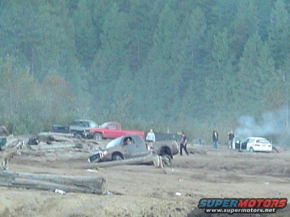 Muddy truck stuck in a dirt field with trees in the background
