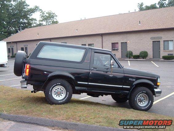 Black 1993 Ford Bronco parked on grass with a building in the background