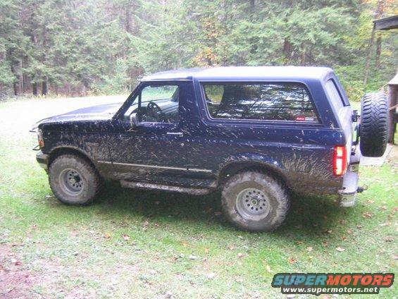 Mud-covered 1994 Ford Bronco, side view. Spare tire mounted on rear