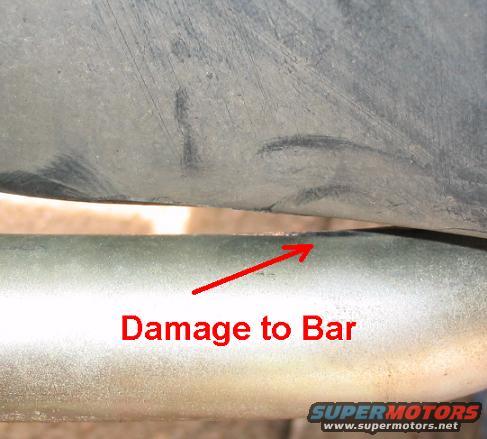 Close-up of damage to a metal bar, with red arrow and text