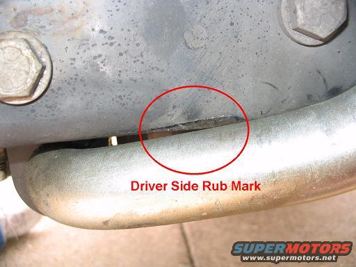Close-up of a metal part with a red circle highlighting a driver side rub mark and text