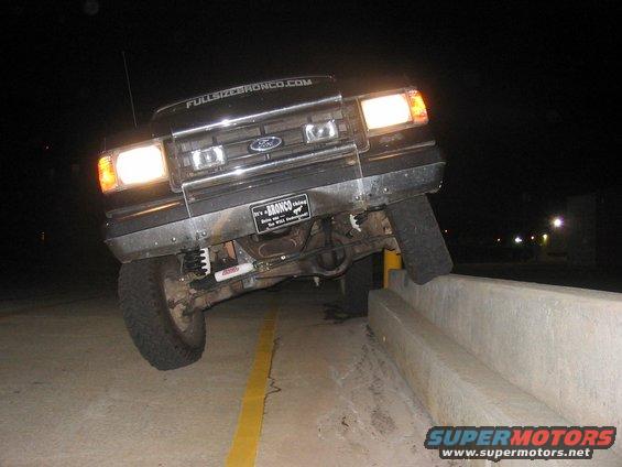 Ford Bronco parked on top of a concrete barrier at night