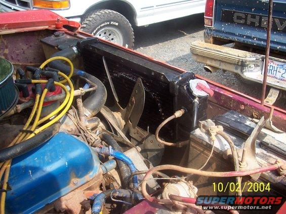 Engine bay with radiator, hoses, and distributor cap. Date stamp reads 10/02/2004