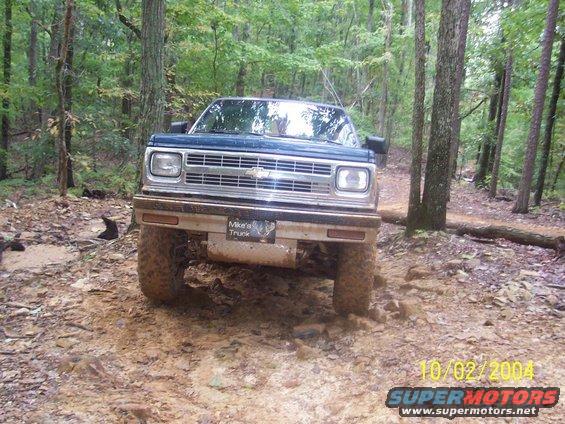 Blue Chevrolet S-10 pickup truck on a muddy, rocky trail, front view. License plate reads 'Mike's Truck'