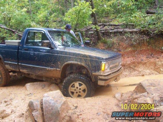 Blue pickup truck stuck in mud, front 3/4 view