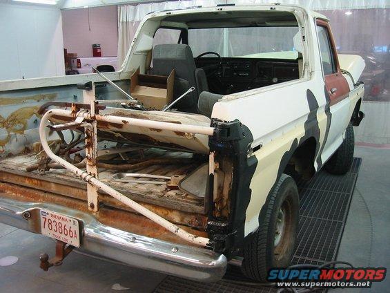 Old Ford Bronco with camo paint, missing tailgate and some rust. Indiana plate visible