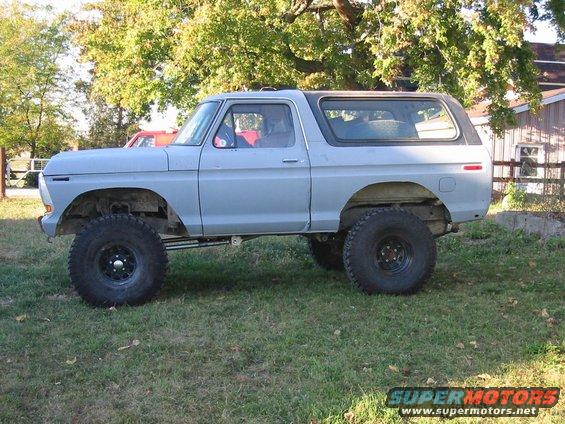 Light blue SUV with large tires parked on grass, side view. Appears to be a 1978 Ford Bronco