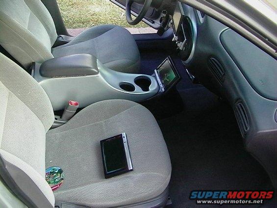 Car interior with gray cloth seats, center console with cup holders, and a tablet mounted on the dashboard