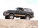 1990 Ford Bronco - This lifted Ford Bronco features a distinctive Confederate flag decal on its rear window, set against a desert landscape.