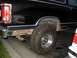 1984 Dodge Ram Van - Rear view of a black 1984 Dodge Ram Van, highlighting significant rust and aftermarket tires.