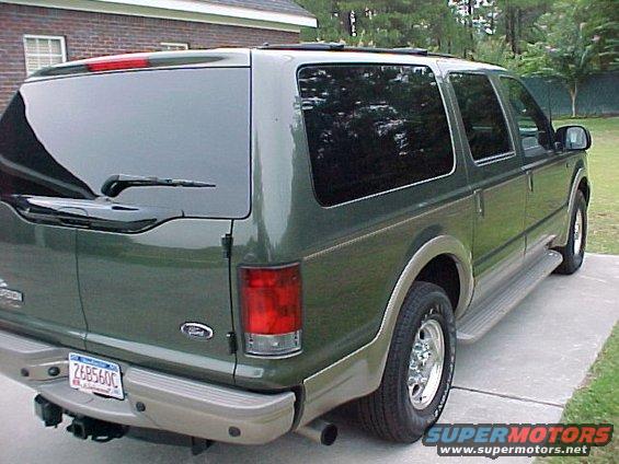 Green Ford Excursion SUV, rear 3/4 view, parked on concrete driveway