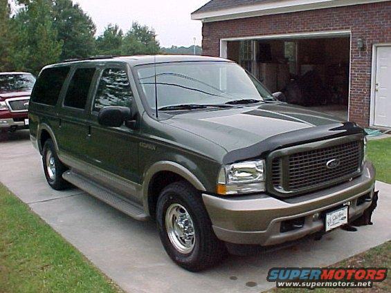 Green Ford Excursion parked in driveway, another truck partially visible on left