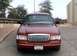 2000 Ford Crown Victoria - Front view of a red 2000 Ford Crown Victoria parked outdoors with a building in the background.