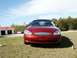2000 Ford Taurus - A red Ford Taurus is parked on a grassy lawn under a blue sky with scattered clouds.