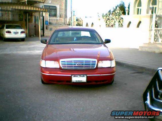 Red 2000 Ford Crown Victoria parked facing forward, with a white car in the background