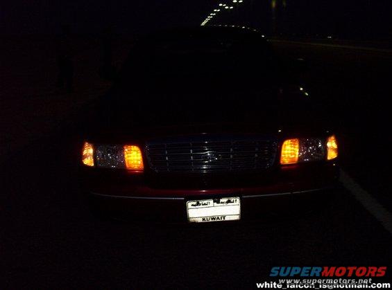 front of red sedan with Kuwait license plate at night