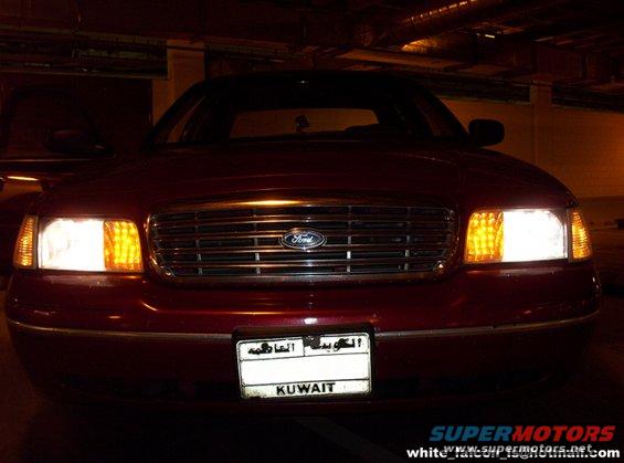 Red Ford Crown Victoria front view with headlights on