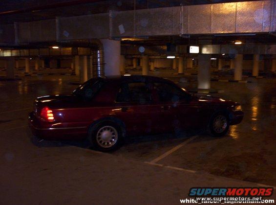 red sedan parked in a dimly lit parking garage, rear quarter view
