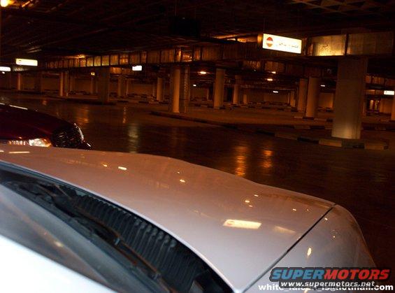 White car hood and windshield in a dimly lit parking garage