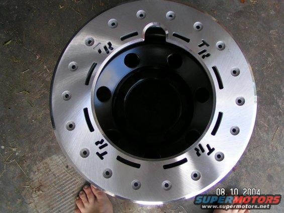 Brake rotor with drilled and slotted design, black hub, and visible text 'TR'