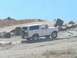 1988 Ford Bronco - A white Ford Bronco navigates a rocky, off-road terrain under a clear blue sky.