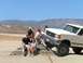 1988 Ford Bronco - A group of people sit on concrete steps next to a white Ford F-Series truck in a dry, mountainous landscape.