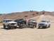 1988 Ford Bronco - Four off-road vehicles are parked in a desert landscape under a clear blue sky.