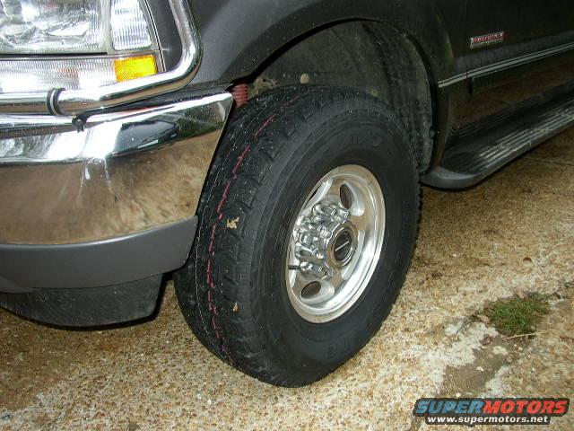 Close-up of a 1999 Ford F-250 Super Duty truck's front wheel, tire, fender, and chrome bumper