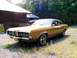1970 Mercury Cougar - A gold 1970 Mercury Cougar is parked on a gravel lot next to a wooden structure.