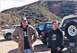 1988 Ford Bronco - Two men pose with several off-road vehicles in a hilly, natural landscape.