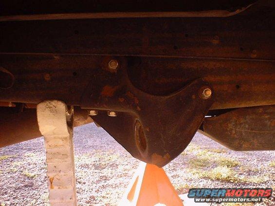 Close-up of rusty vehicle frame with suspension bracket held up by jack stands