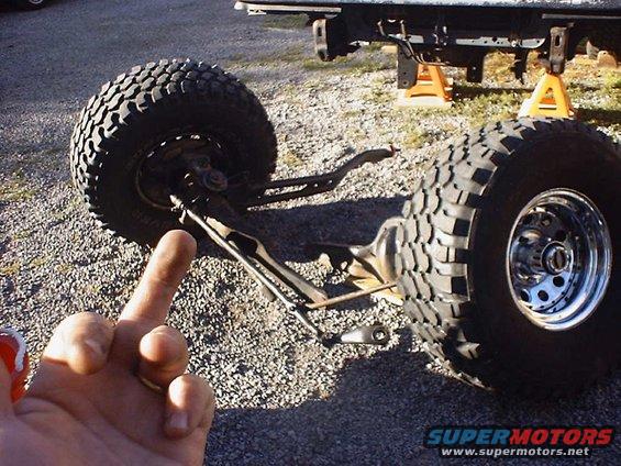 Front suspension assembly with large tires, one chrome rim visible