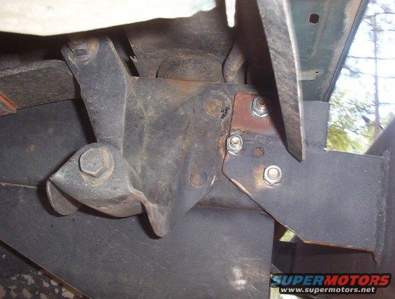 Close-up of rusted metal bracket with bolts, likely part of a vehicle's undercarriage