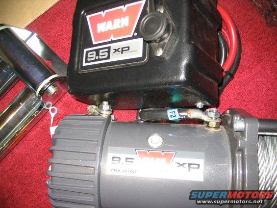Warn 9.5 XP winch with chrome bars and red/black cables on a red surface