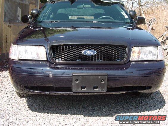 Dark blue Ford Crown Victoria front view, honeycomb grille, aftermarket headlights, license plate bracket