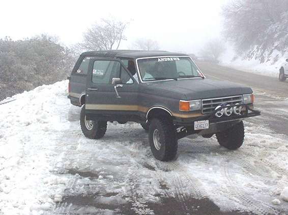 Ford Bronco parked on a snowy road, driver's door open