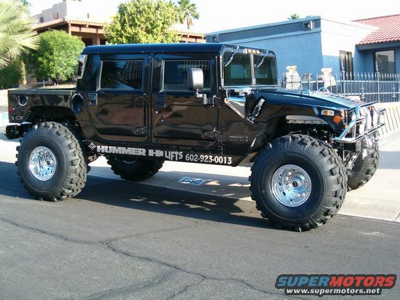 Black Hummer H1 with large tires and "HUMMER H1 LIFTS" text on the side