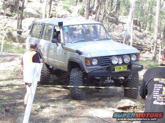 Silver Toyota Land Cruiser with snorkel and off-road tires navigating rocky terrain