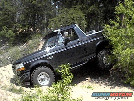 Black Ford Bronco with lifted suspension and off-road tires driving on a dirt hill