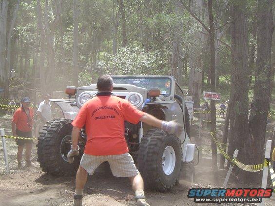 Off-road vehicle with large tires navigating a dusty course