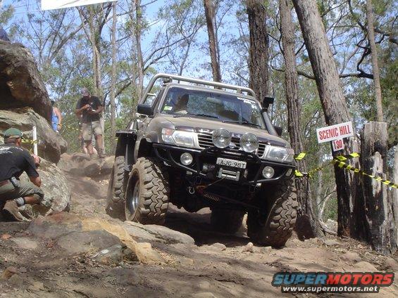 Brown off-road SUV with large tires and winch, navigating a rocky trail