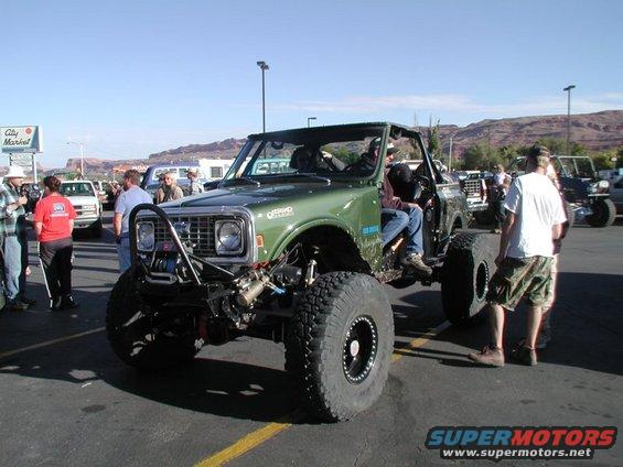 Modified green SUV with large tires and off-road bumper. 1970s model year suggested by grille